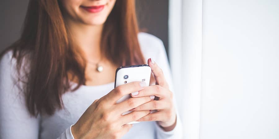 Chica utilizando smartphone para subir la temperatura de su termpostato